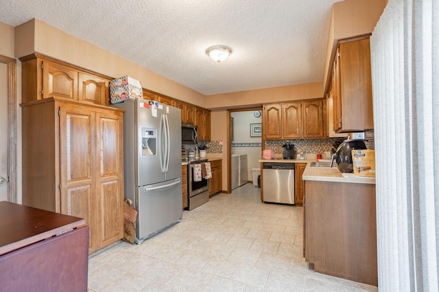 945 Ozark Rd, Nixa, MO 65714 - kitchen with a textured ceiling, brown cabinets, stainless steel appliances, backsplash, and independent washer and dryer
