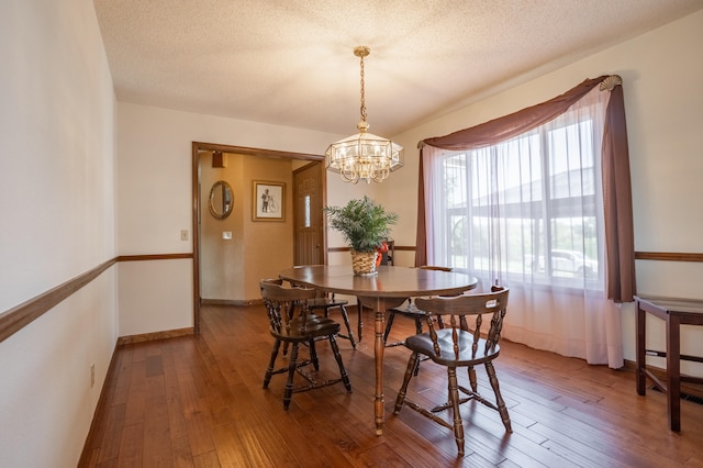 dining space featuring hardwood / wood-style floors, an inviting chandelier, and a textured ceiling