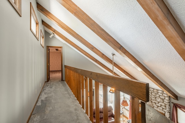 corridor featuring vaulted ceiling with beams, a textured ceiling, and carpet