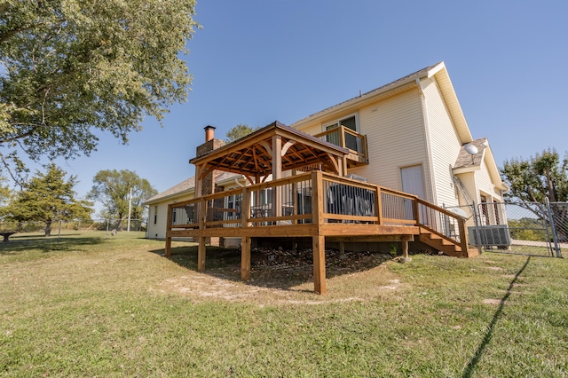 rear view of property with a yard, a wooden deck, and central AC