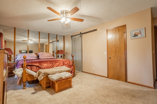 bedroom featuring a barn door, carpet, a textured ceiling, and ceiling fan