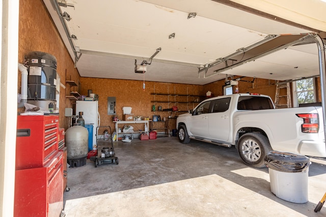 garage with white refrigerator, a garage door opener, and electric panel