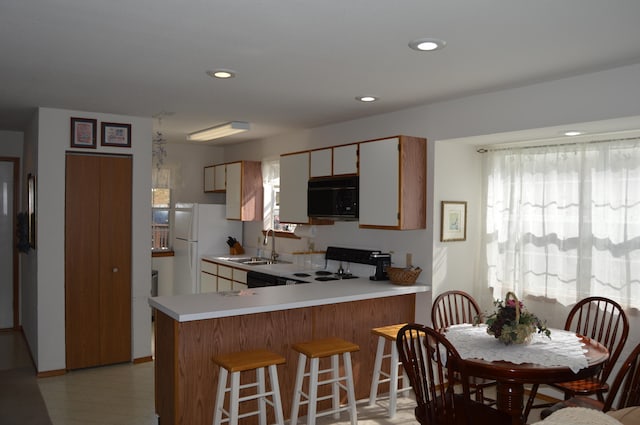 kitchen with stove, kitchen peninsula, sink, and white fridge