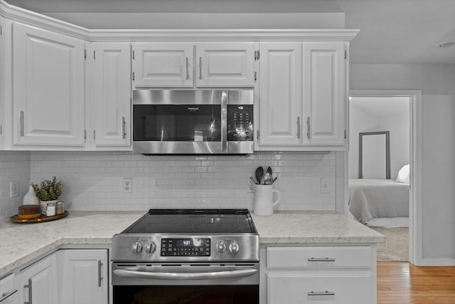 kitchen with appliances with stainless steel finishes, light hardwood / wood-style floors, tasteful backsplash, and white cabinetry