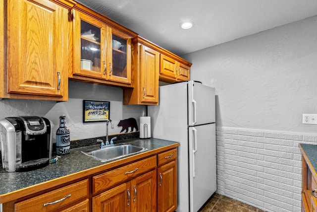 kitchen with white refrigerator, dark tile patterned floors, and sink