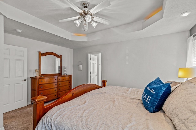 carpeted bedroom featuring a tray ceiling and ceiling fan