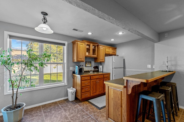 kitchen with a kitchen breakfast bar, decorative light fixtures, sink, kitchen peninsula, and white fridge