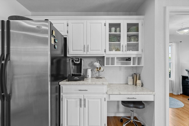 kitchen featuring backsplash, stainless steel fridge, light wood-type flooring, and white cabinetry