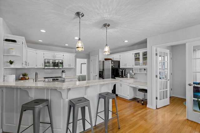 kitchen with appliances with stainless steel finishes, light wood-type flooring, and white cabinets