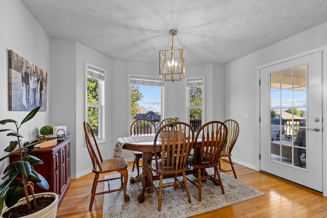 dining space featuring plenty of natural light, an inviting chandelier, and light wood-type flooring