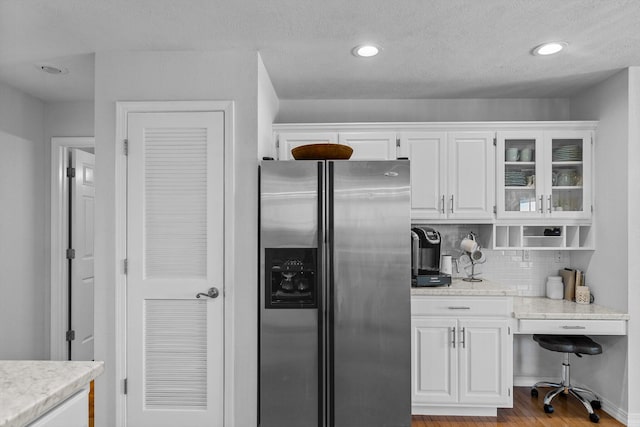 kitchen featuring stainless steel fridge, light hardwood / wood-style floors, and white cabinetry