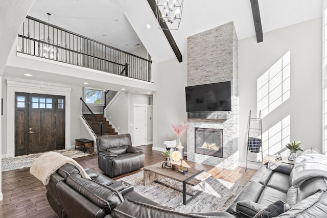 living room with beam ceiling, high vaulted ceiling, hardwood / wood-style flooring, a notable chandelier, and a fireplace