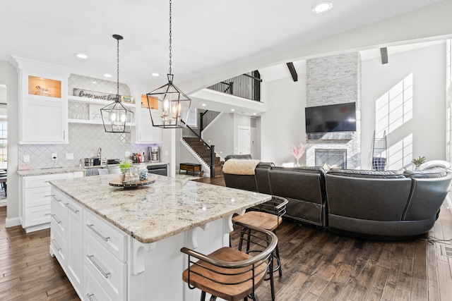 kitchen featuring a center island, dark hardwood / wood-style flooring, white cabinetry, a kitchen bar, and decorative light fixtures