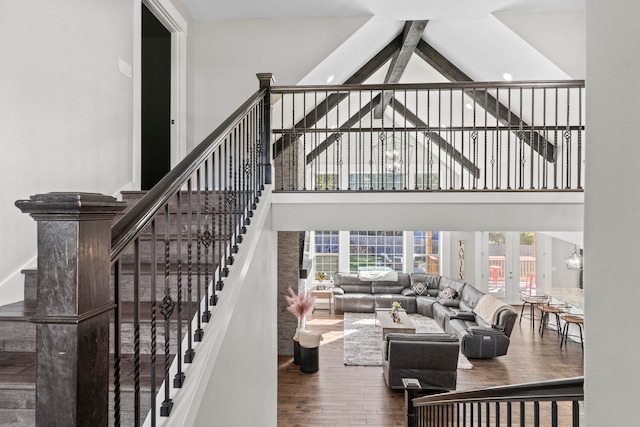 living room with wood-type flooring, high vaulted ceiling, beam ceiling, and a notable chandelier