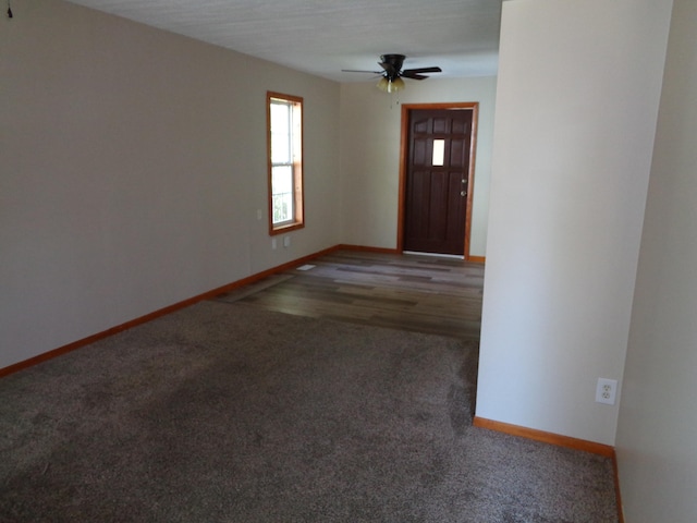 foyer entrance with ceiling fan and dark wood-type flooring