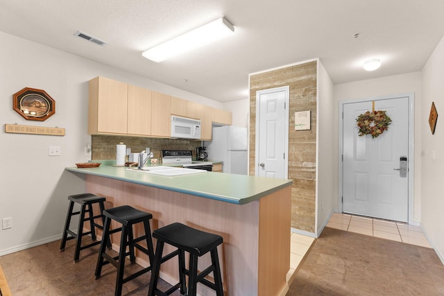 34 Golfshores Dr Unit 8, Branson, MO 65616 - kitchen with a sink, light brown cabinetry, white appliances, a kitchen bar, and a peninsula