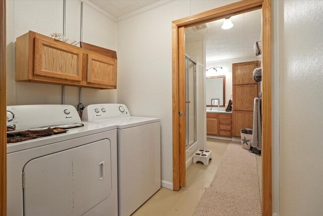 washroom with washing machine and dryer, ornamental molding, and cabinet space