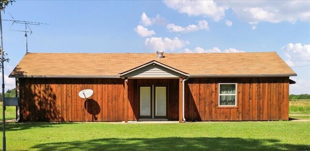 back of house featuring board and batten siding, a lawn, and a shingled roof