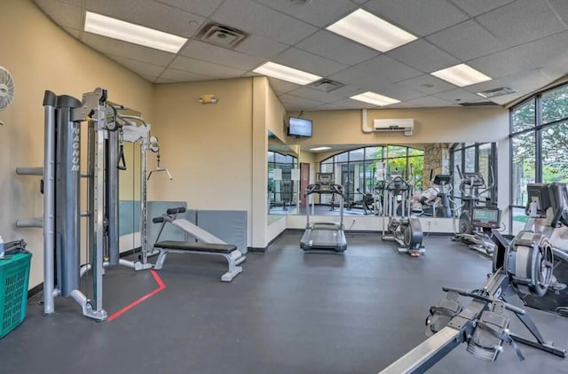 workout area featuring a drop ceiling and a wall mounted air conditioner