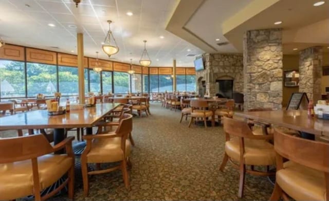 carpeted dining room with decorative columns and a healthy amount of sunlight