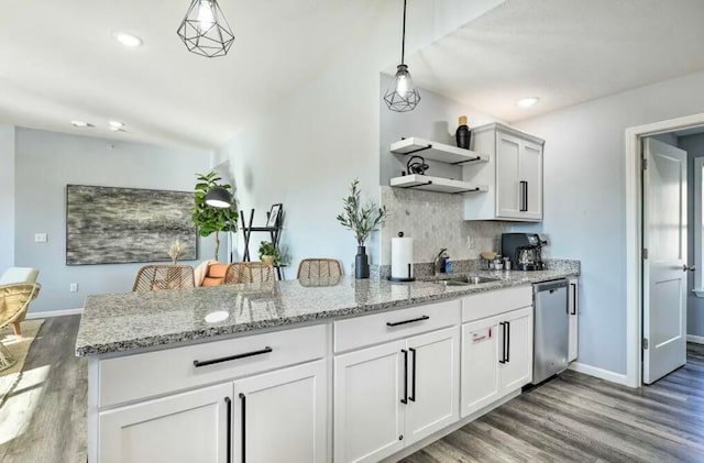 kitchen featuring kitchen peninsula, hanging light fixtures, hardwood / wood-style flooring, stainless steel dishwasher, and white cabinetry