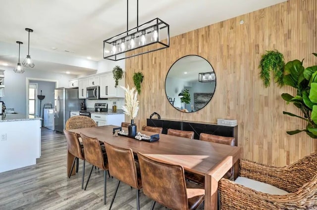 dining area with wooden walls, sink, and light hardwood / wood-style flooring