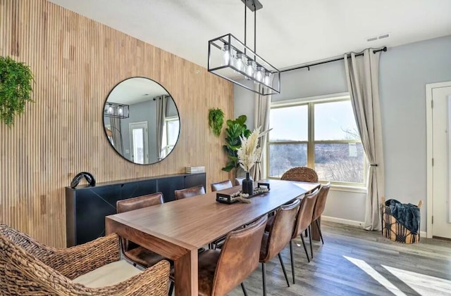 dining area with hardwood / wood-style floors and wooden walls