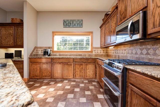 kitchen with appliances with stainless steel finishes, light stone countertops, and backsplash