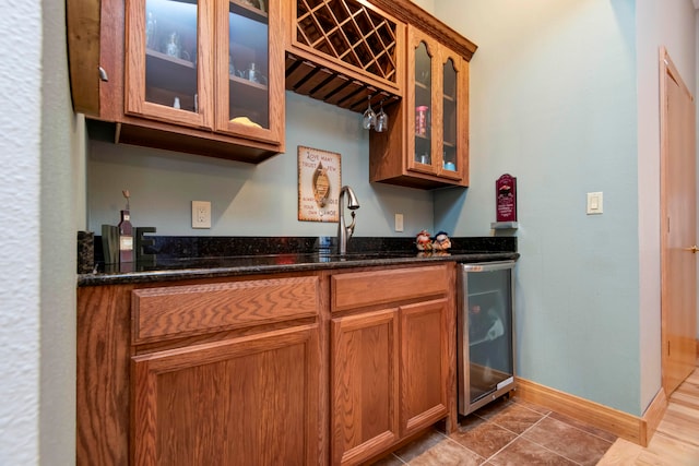 kitchen featuring dark stone countertops, beverage cooler, sink, and tile patterned flooring