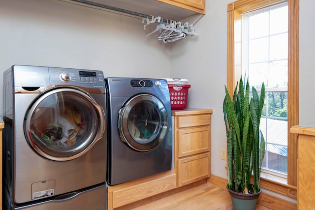 laundry area featuring cabinets, light hardwood / wood-style floors, and washer and dryer