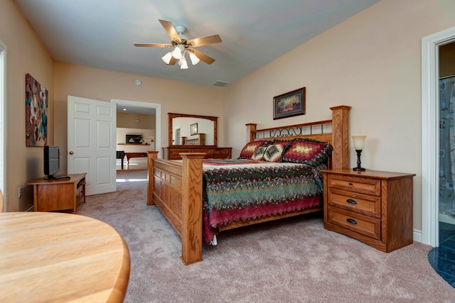 bedroom with light carpet, ensuite bathroom, and ceiling fan