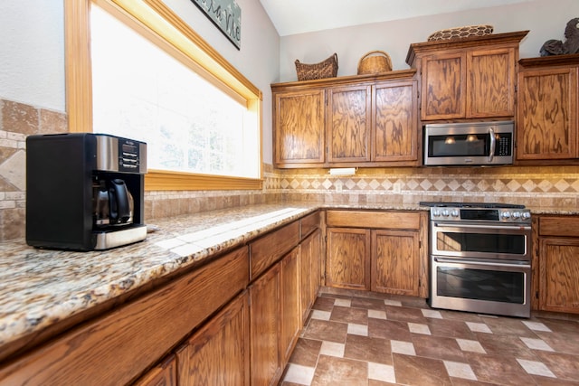 kitchen featuring appliances with stainless steel finishes, light stone counters, and decorative backsplash