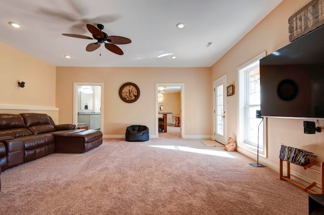 living room with ceiling fan, light colored carpet, and a wealth of natural light