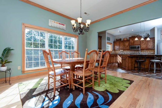 dining area featuring light hardwood / wood-style flooring, crown molding, and a notable chandelier