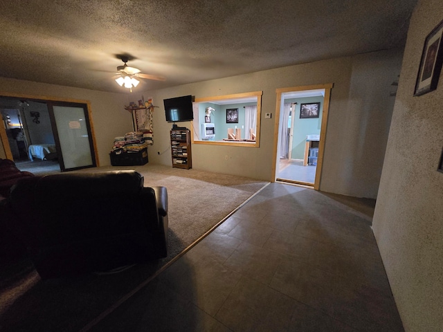 carpeted living room featuring ceiling fan and a textured ceiling