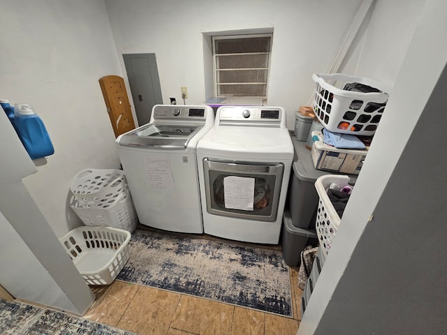 washroom with electric panel, independent washer and dryer, and hardwood / wood-style floors