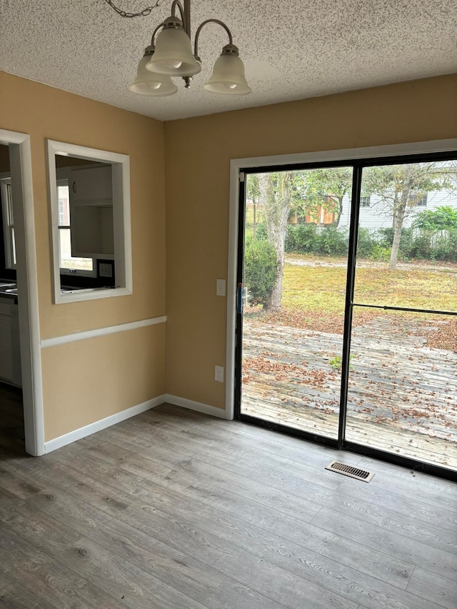 spare room with wood-type flooring, a notable chandelier, and a textured ceiling