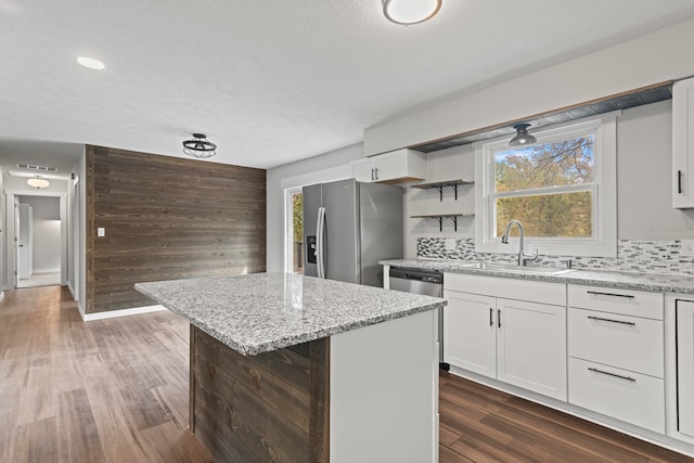 kitchen featuring appliances with stainless steel finishes, sink, a kitchen island, white cabinetry, and decorative backsplash