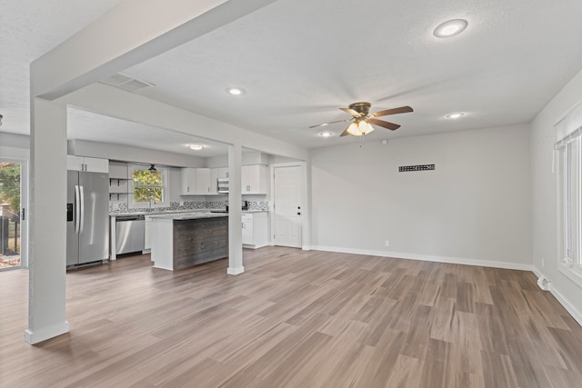 unfurnished living room featuring ceiling fan, a textured ceiling, and light wood-type flooring