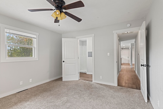 unfurnished bedroom featuring ensuite bath, carpet flooring, and ceiling fan