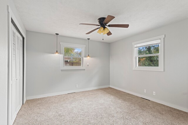 unfurnished bedroom featuring a closet, ceiling fan, a textured ceiling, and carpet floors