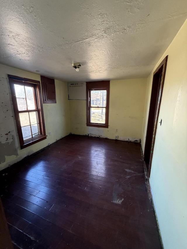 spare room featuring a healthy amount of sunlight, dark hardwood / wood-style floors, and a textured ceiling