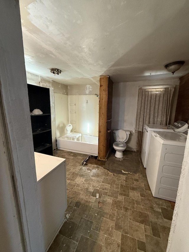 bathroom with washer and dryer and a tub