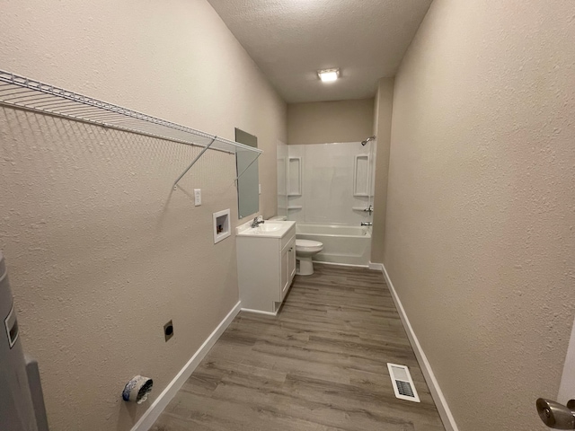 clothes washing area with sink, hookup for an electric dryer, wood-type flooring, a textured ceiling, and hookup for a washing machine