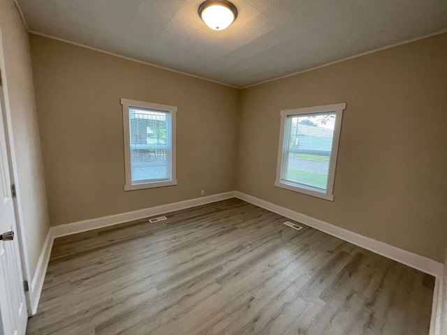 empty room with crown molding and light hardwood / wood-style floors