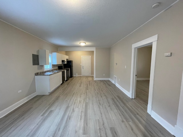 kitchen with light wood-type flooring, sink, black refrigerator, electric panel, and white cabinetry