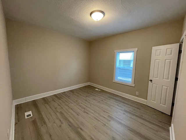 unfurnished room with light hardwood / wood-style floors and a textured ceiling