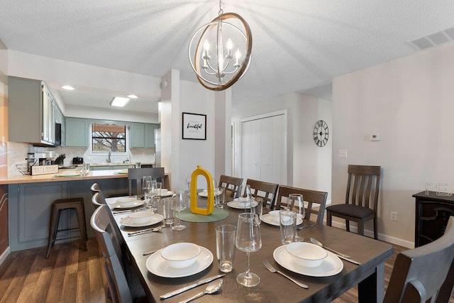 dining area with an inviting chandelier, sink, dark hardwood / wood-style flooring, and a textured ceiling