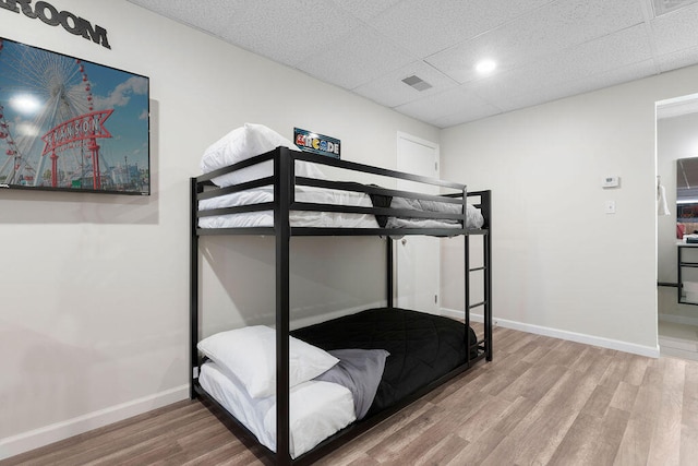 bedroom featuring a drop ceiling and wood-type flooring