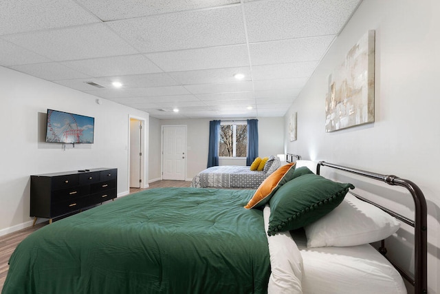 bedroom featuring a drop ceiling and hardwood / wood-style floors